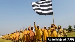 Ansar-ul Islam, the stick-wielding volunteers of Jamiat Ulema-e Islam Fazal (JUI-F) party raise hands as they prepare for the freedom march in Peshawar on October 13.