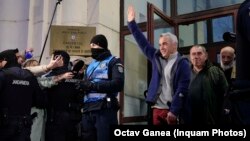 Călin Georgescu salută mulțimea la ieșirea din Parchetul General. Fostul candidat extremist la alegerile românești de anul trecut a fost pus sub control judiciar.