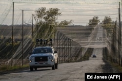 خودرویی مجهز به تجهیزات پارازیت سیگنال در جاده‌ای استتارشده با تورهای ضدپهپاد در شرق اوکراین حرکت می‌کند