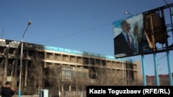 Пострадавшее здание офиса компании «Озенмунайгаз» и испорченный билборд с изображением президента Назарбаева.  Жанаозен, 19 декабря 2011 года. 