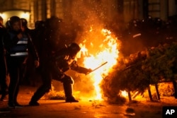 Poliția încearcă să stingă un incendiu declanșat în timpul ciocnirilor cu susținătorii lui Călin Georgescu, la București.