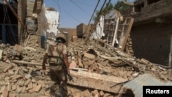FILE: A Pakistani soldier walks in a house destroyed during a military operation in the of town of Miran Shah, North Waziristan in July 2014.