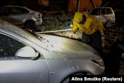 Чоловік оглядає своє авто, що зазнало ушкоджень внаслідок російської атаки на Київ, 14 листопада 2025 року