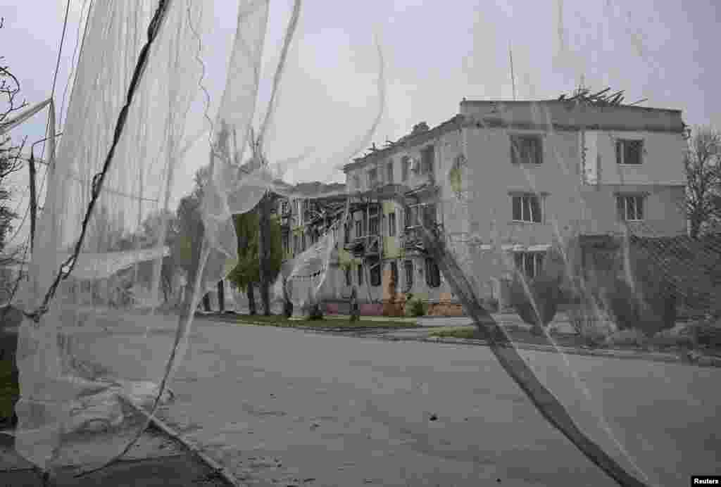 Станбена зграда оштетена од руските воздушни напади и мрежа против дронови поставена на улицата пред неа, во градот Орихив, Запорошка област. 13 ноември 2025 година.