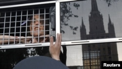 An opposition activist looks out from a police bus after being detained near a protest camp on May 17.