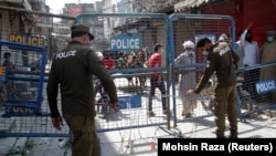 Police officers put up barriers as they guard a street sealed after authorities reimposed lockdowns in selected areas in an effort to stop the spread of the coronavirus disease in the eastern city of Lahore on June 17.
