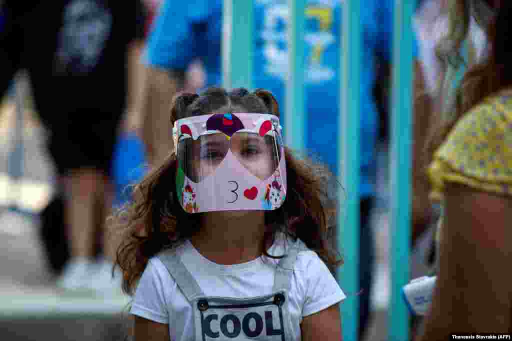 A pupil wearing a face shield arrives at a primary school on the first day of class of the new academic year in the Greek capital, Athens, on September 14.