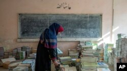 یک آموزگار افغان در حال جمع کردن کتاب‌های درسی در مدرسه‌ای در کابل، دسامبر ۲۰۲۲ 