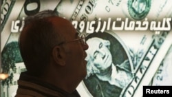 An Iranian man walks past a currency-exchange shop in northern Tehran. Sanctions on Iran have caused the rial to plunge in value, driving up the cost of imports.