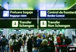 Подорожувальники йдуть повз нещодавно встановлені знаки, що вказують на Шенгенську та нешенгенську зони. Румунія, 31 березня 2024 року