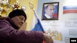 A woman casts her ballot in front of a portrait of Russian President Vladimir Putin at a polling station at a local school in Moscow on September 18.