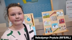 Стефанія Єсипенко, 10-річна дочка фрілансера Крим.Реалії Владислава Єсипенка біля свого малюнка, де зображено її родину. Київ, 5 червня 2025 року