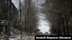 Місцеві жителі йдуть повз зруйновані російськими обстрілами будинки у Покровську, 12 квітня 2025 року