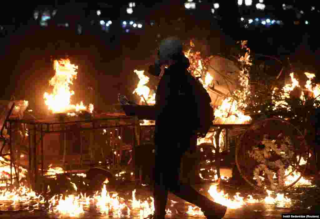 Протестующий в противогазе идет рядом с горящей баррикадой во время митинга оппозиции в день местных выборов в Тбилиси, Грузия, 4 октября 2025 года. REUTERS/Ираклий Геденидзе