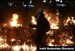 Протестующий в противогазе проходит рядом с горящими баррикадами, Тбилиси, Грузия, 4 октября 2025 года