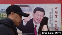 Oameni pe stradă la Beijing, lângă un poster cu președintele Xi Jinping. 26 februarie 2018