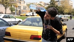 An Iranian taxi driver cools down by splashing water on his face on a street amid soaring temperatures in Tehran on July 22.