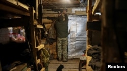 Un soldat ucrainean își îngrijește pușca de asalt într-un adăpost subteran, într-o poziție de pe linia frontului, lângă orașul Kramatorsk (imagine ilustrativă).