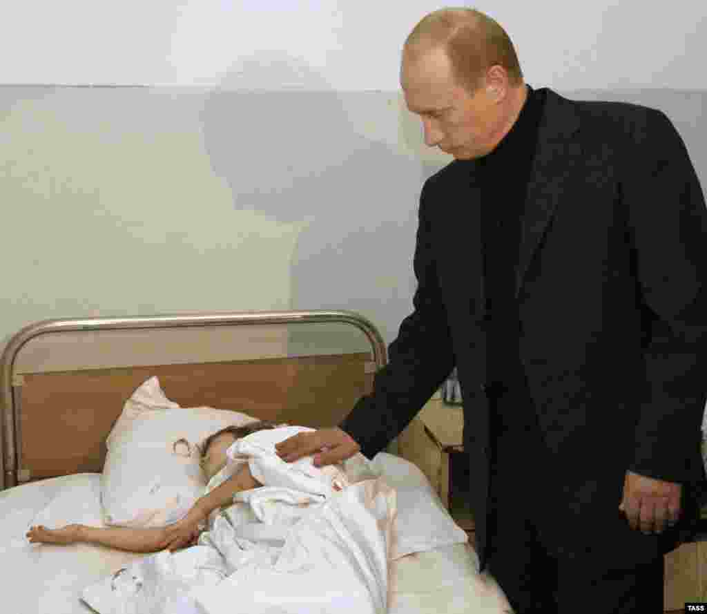 Președintele Vladimir Putin vizitează un copil rănit în timpul asediului de la Beslan, în septembrie 2004.