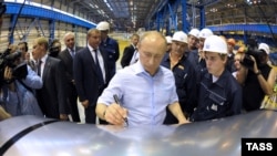 Президент России Владимир Путин оставляет автограф на металлическом  листе во время посещения Магнитогорского металлургического комбината на Южном Урале (2012 год). Казахстанское предприятие отказалось поставлять сырье на этот комбинат после начала вторжения России в Украину 