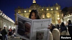 O femeie citește anunțul morții Papei Francisc în ziarul „L'Osservatore Romano" în Piața Sfântul Petru de la Vatican, pe 21 aprilie 2025. 