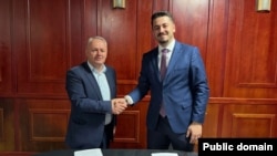 Agron Kuçi i AAK-së (majtas) duke shtrënguar duart me Jetmir Tofajn e LVV-së pas arritjes së koalicionit në Junik. Më 9 nëntor, Kuçi përballet me kandidatin e LDK-së, Ruzhdi Shehun.