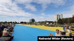 Огромный украинский флаг в руках у демонстрантов, вышедших на улицу в Анкоридже в день приезда Путина. 15 августа 2025 года