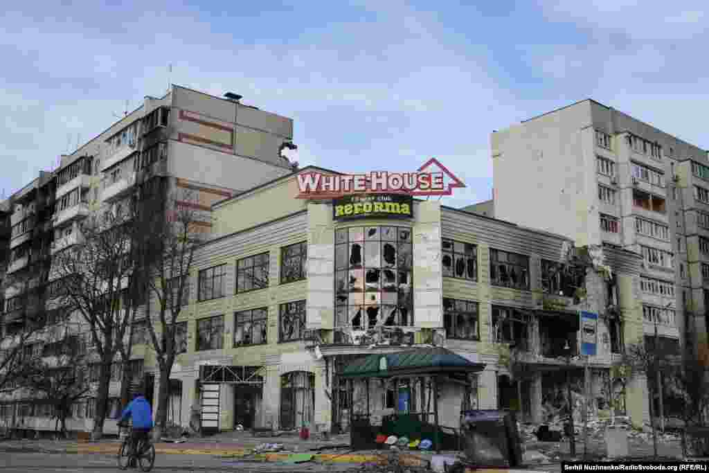 Пошкоджений обстрілами торговий центр на Гостомельському шосе. Зараз цю будівлю відновили. Житлові багатоповерхівки позаду, які було пошкоджено внаслідок обстрілів – демонтували.Ліворуч фото від 7 квітня 2022, праворуч – березень 2025 року