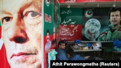 A vendor sits next to images of cricket star-turned-politician Imran Khan, chairman of Pakistan Tehreek-e Insaf (PTI) at a market in Islamabad on July 27.