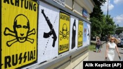 Люди проходять біля плакатів у столиці Польщі в розпал збройної агресії Росії проти України. Варшава, 14 липня 2014 року