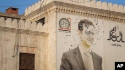 په حما کې د ولایتي حکومت پر دفتر د ولسمشر بشار الاسد انځور په مرمیو ویشتل شوی دی - د ډېسېمبر شپږمې انځور.