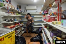 Жінка збирає товар з полиць продуктового магазину, оскільки він закривається через наступ російських військ, Покровськ, 23 серпня 2023 року