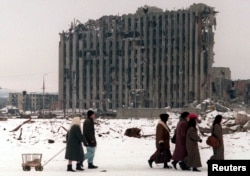 Stanovnici prolaze pored uništene predsjedničke palače u Groznom, februar 1996.