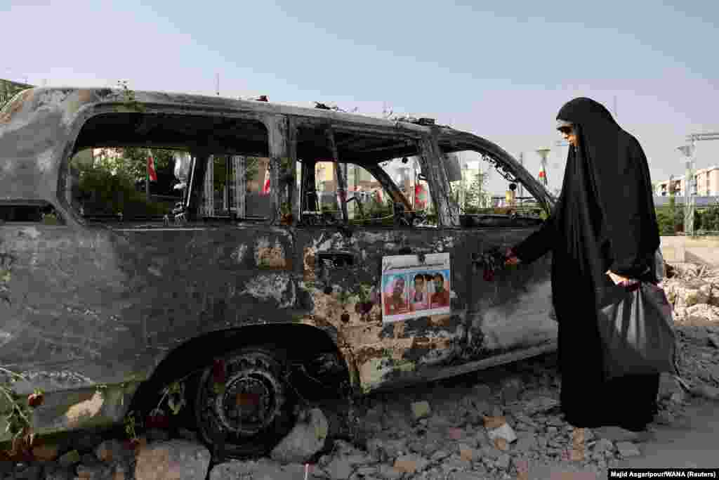 Израилдин аба соккуларынан кийин күйүп кеткен машиненин жанында турган ирандык аял. Тегеран, Иран. 