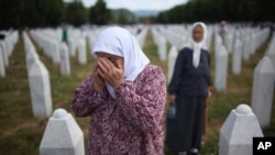 A woman mourns at the grave of her relative, a victim of the Srebrenica genocide, at the Memorial Center in Potocari, Bosnia, Friday, July 11, 2025.
