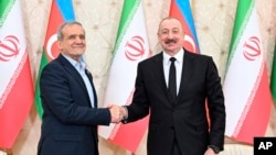 Azerbaijani President Ilham Aliyev (right) and Iranian President Masoud Pezeshkian shake hands after a joint news conference following talks in Baku on April 28, 2025.