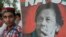  supporters of Pakistan's cricketer-turned politician and head of the Pakistan Tehreek-e-Insaf (Movement for Justice) party Imran Khan stands next to poster with a picture of Khan as they gather near his residence in Islamabad on July 26.