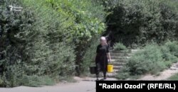 Тажикстандын Куляб шаарындагы аял чака менен суу көтөрүп баратат.