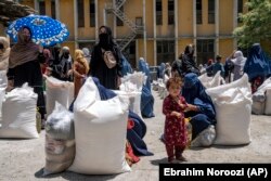 Gratë afgane duke marrë pako ushqimore që i shpërndau një grup i ndihme humanitare, në Kabul, Afganistan, maj 2023.