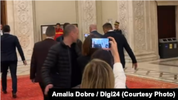 Jurnaliști împiedicați de un ofițer de presă al Guvernului să-i adreseze întrebări premierului Ilie Bolojan, pe holurile Parlamentului, pe 26 noiembrie 2025.