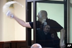 მელია მოსამართლეს წყალს ასხამს - ბრალდებულის საკნის შუშა მოსამართლე ირაკლი შვანგირაძეს ირეკლავს.