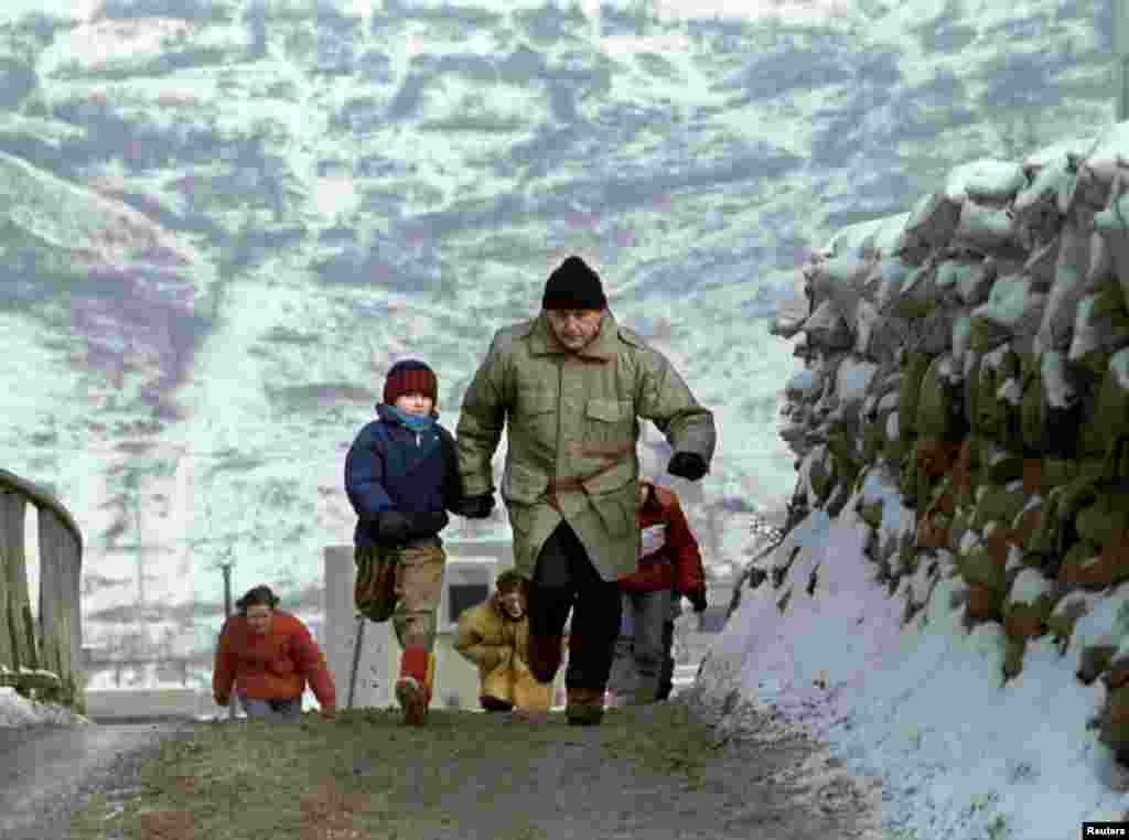 In an attempt to dodge snipers, a father and son sprint across a sandbagged bridge in the Olympic village area of Dobrinja, on January 4, 1993.