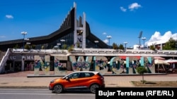 Një makinë duke kaluar pranë obeliskut Newborn në Prishtinë. 