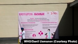 Врачи идут рядом с баннером во время дополнительных кампаний по иммунизации в ответ на вспышку кори. Фото: ВОЗ/Даниль Усманов