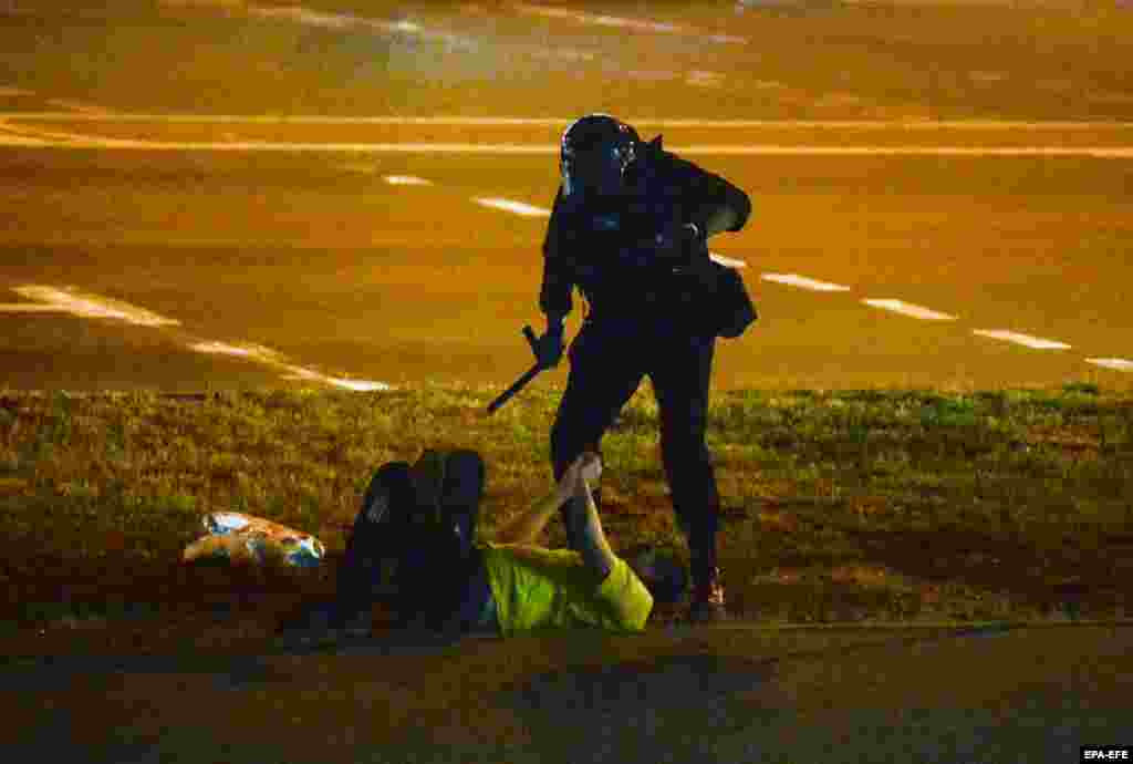 A police officer stands over a man on the ground in Minsk on August 12.
