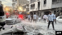 People and first-responders gather outside a building that was hit by an Israeli strike in Tehran on June 13, 2025.