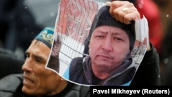 A man holds a photo of Kazakh activist Dulat Aghadil during a commemoration meeting in Almaty on February 27.
