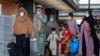 Families evacuated from Kabul, Afghanistan, walk through the terminal to board a bus after they arrived at Washington Dulles International Airport, in Chantilly, Va., Sept. 1, 2021