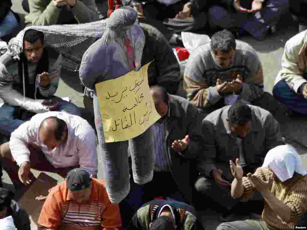 Antigovernment protesters take part in Friday Prayers next to an effigy of President Hosni Mubarak on Tahrir Square.