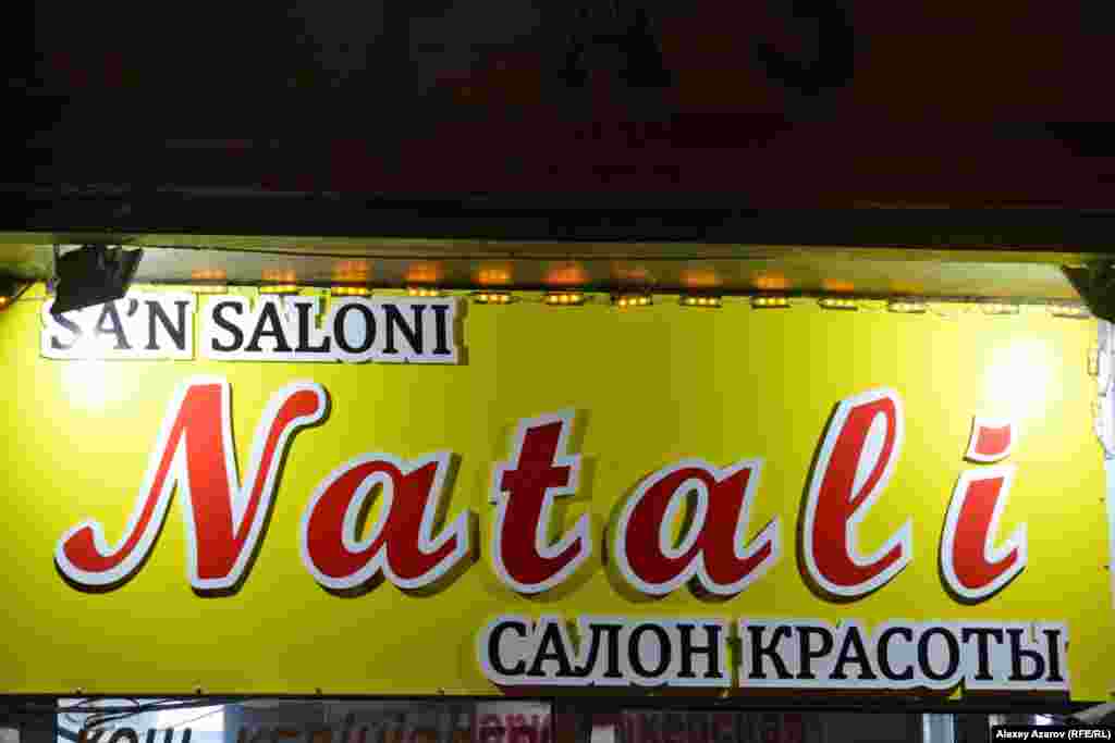 На смену варианту с диграфами уже через месяц (26 октября 2017 года) пришел вариант с обилием апострофов. Он тоже не прижился и продержался только до февраля 2018 года. Но кое-где успели появиться вывески на латинице с апострофами. По этой вывеске можно узнать, что казахская латиница появилась на ней вскоре после принятия варианта с апострофами, то есть довольно оперативно. На это указывает слово Sa'n c апострофом для передачи звука [ә]. Но вывеска продолжала висеть даже после того, как апострофы исключили из алфавита, по крайней мере до 2 декабря 2018 года, когда было сделано это фото. Во втором же слове на латинице допущена орфографическая ошибка (об этой ошибке подробнее говорится ниже).